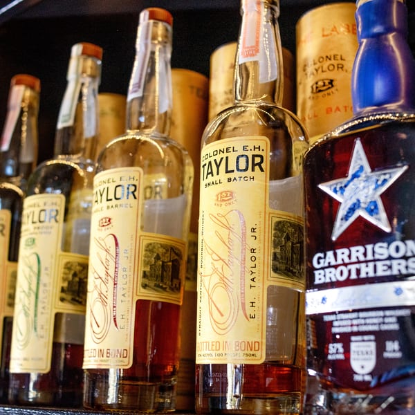 A close-up of several bottles of Colonel E.H. Taylor and Garrison Brothers bourbon whiskey.