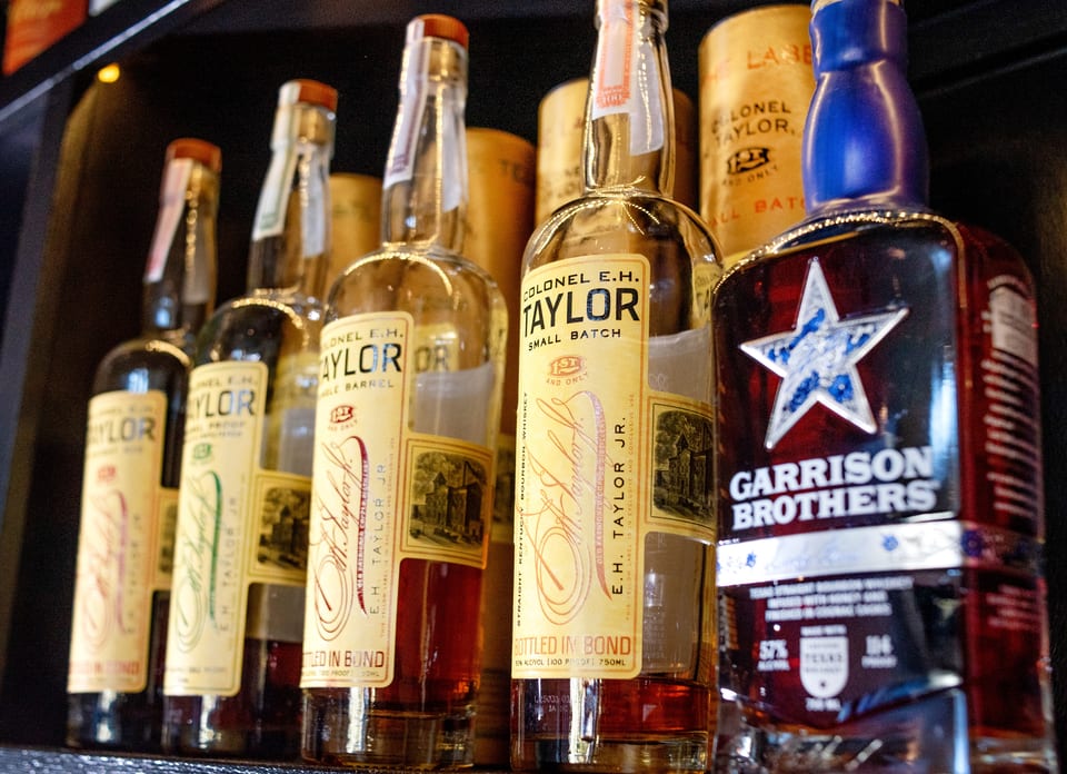 A close-up of several bottles of Colonel E.H. Taylor and Garrison Brothers bourbon whiskey.